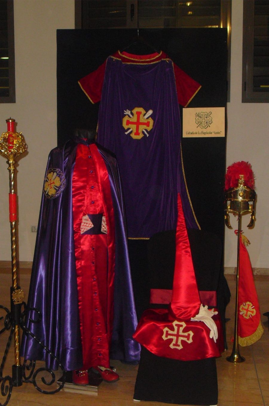 Túnica y capirote rojos, capa morada y vara de la Cofradía «Los Azotes», expuestos.
